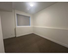 A room with a carpeted floor and a window with blinds.
