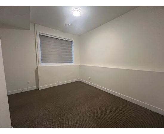 A room with a carpeted floor and a window with blinds.