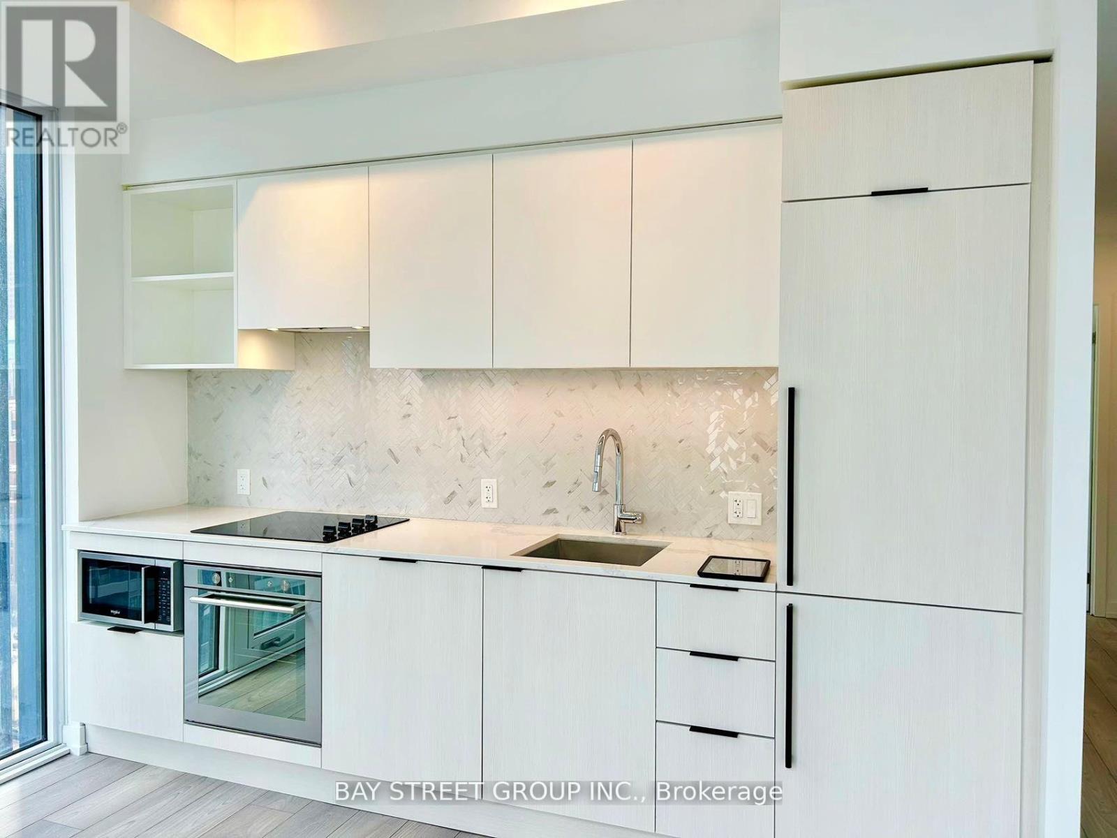 A modern kitchen with white cabinets and a marble backsplash.