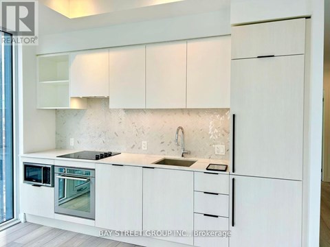 A modern kitchen with white cabinets and a marble backsplash.