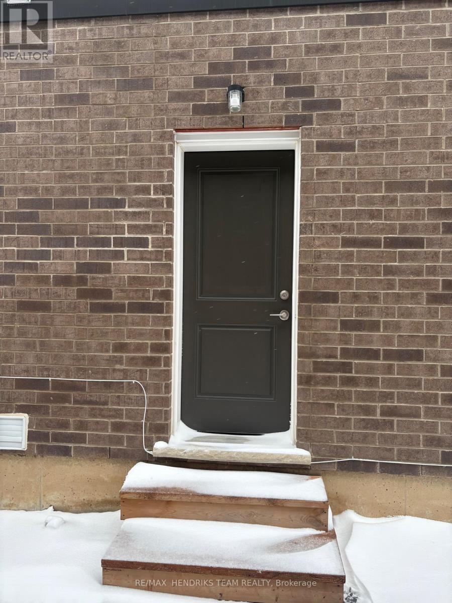 A black door with a white frame is set in a brick wall.