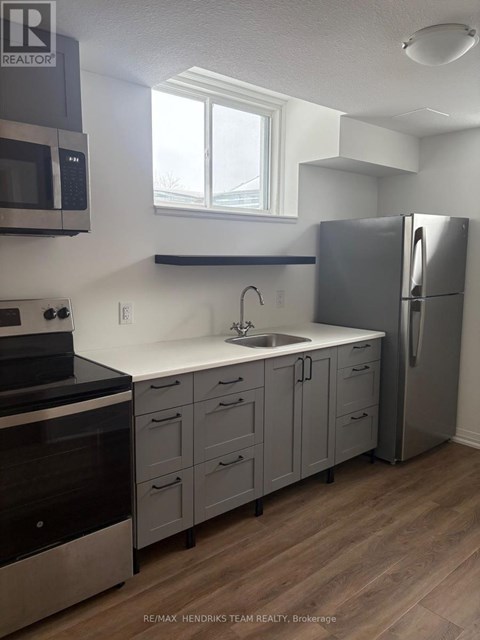 A kitchen with a refrigerator, sink, and cabinets.