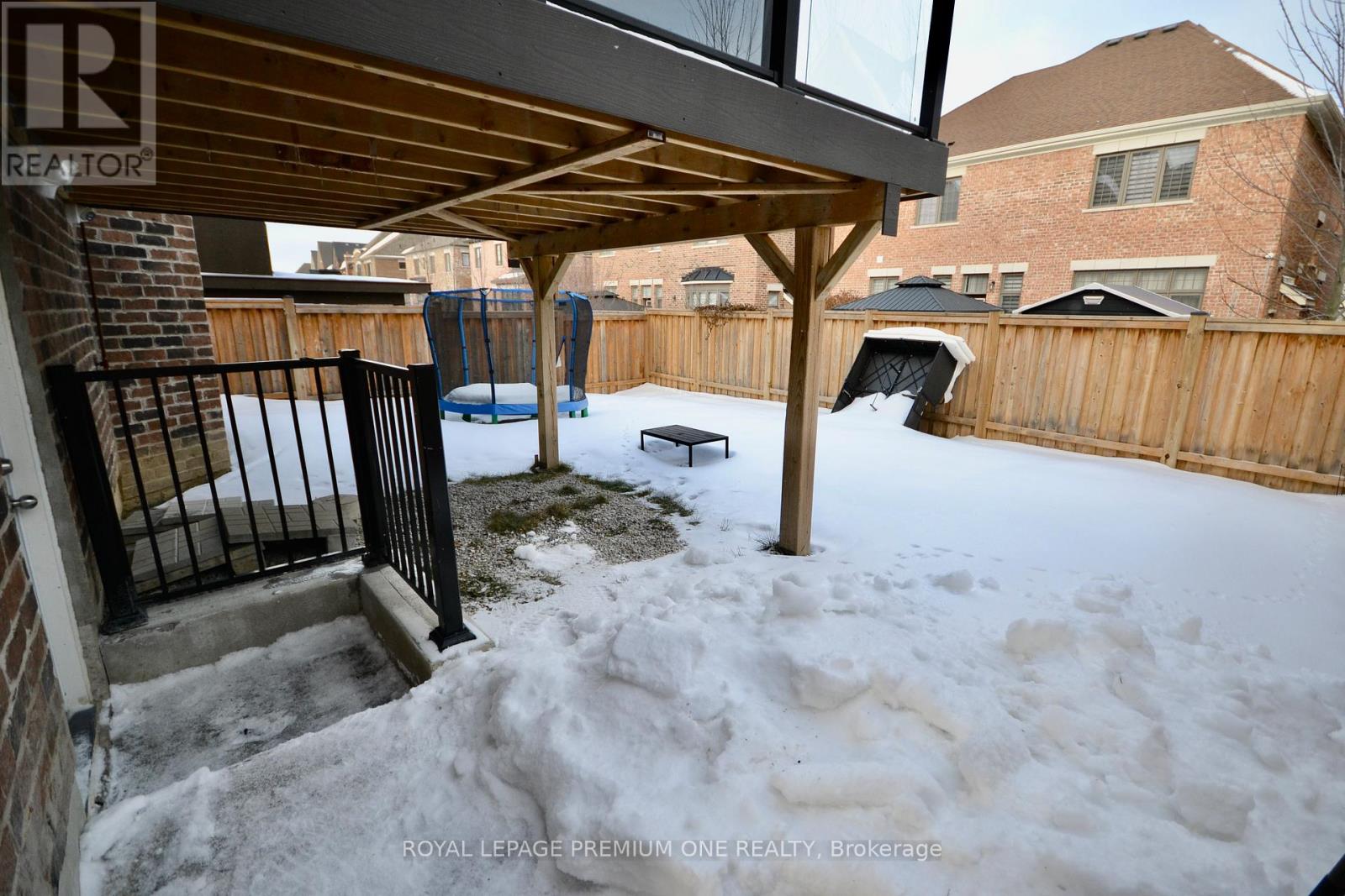 A backyard with a wooden deck and a hot tub covered in snow.