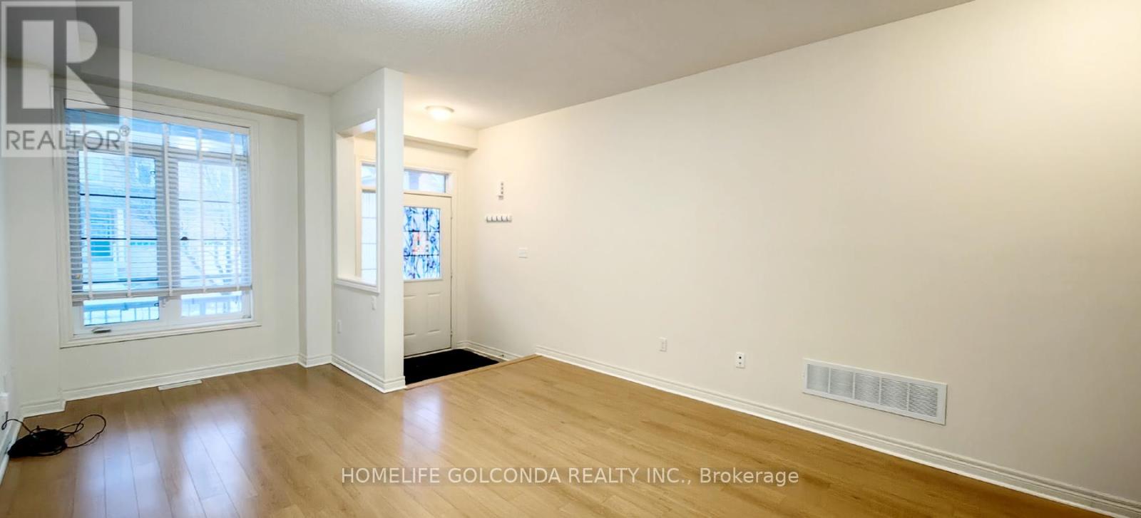 A spacious room with wooden floors and white walls.