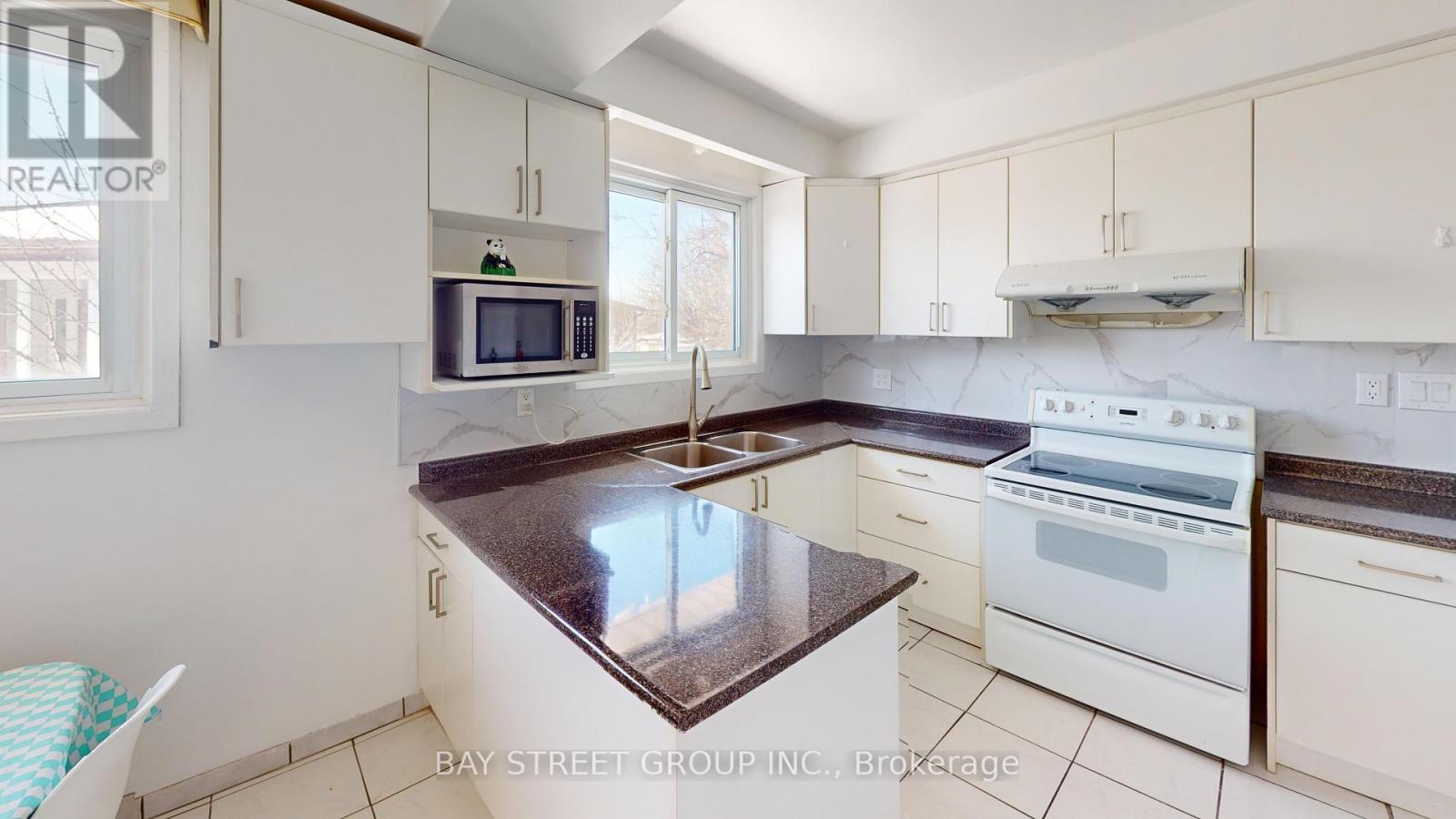 A kitchen with white cabinets and a marble countertop.