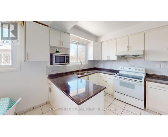 A kitchen with white cabinets and a marble countertop.