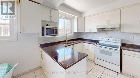 A kitchen with white cabinets and a marble countertop.