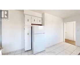 A white refrigerator in a kitchen with white cabinets.