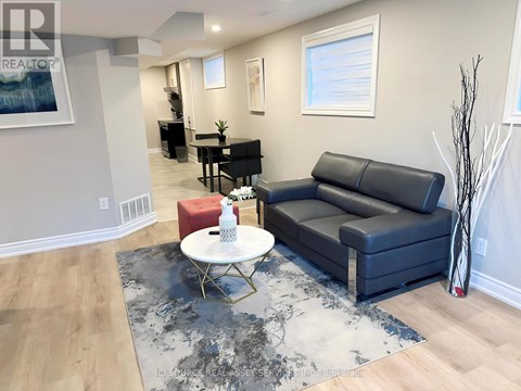 A living room with a black leather couch, a white coffee table, and a rug with a black and white pattern.
