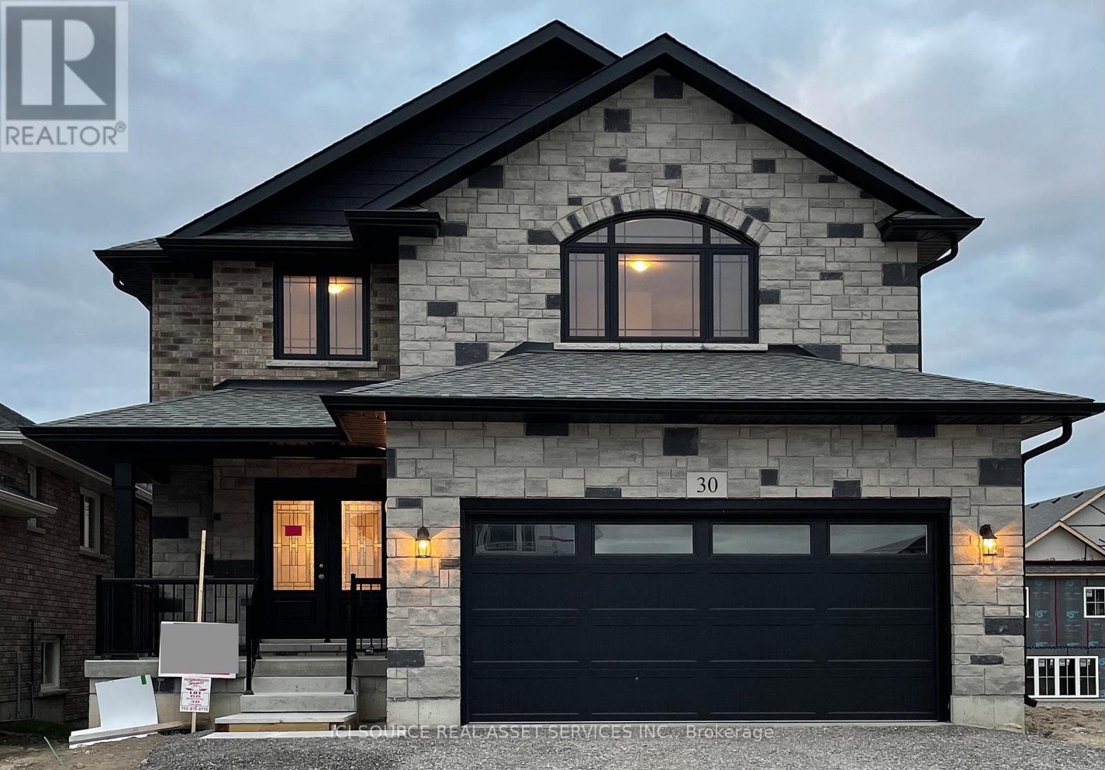 A modern house with stone exterior and a black garage door is for sale.