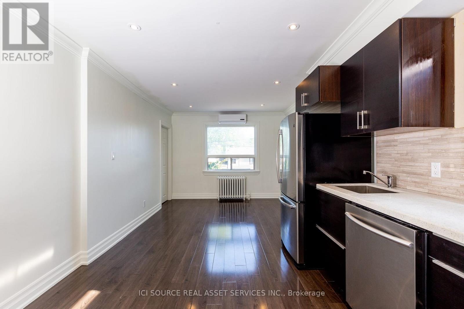 A kitchen with dark wood cabinets and a stainless steel dishwasher.