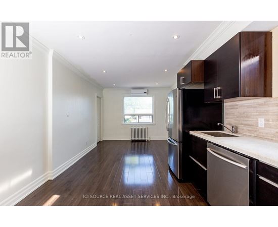 A kitchen with dark wood cabinets and a stainless steel dishwasher.