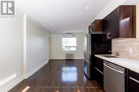 A kitchen with dark wood cabinets and a stainless steel dishwasher.