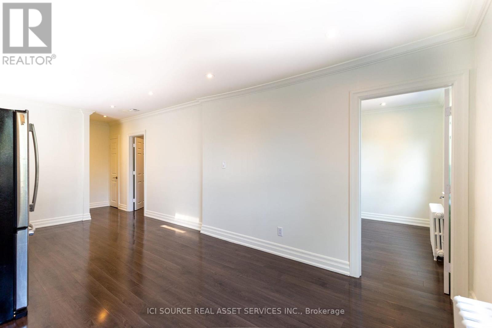 A spacious room with wooden floors and white walls.