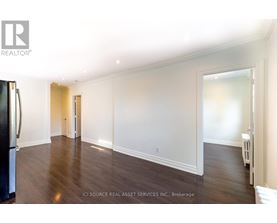 A spacious room with wooden floors and white walls.