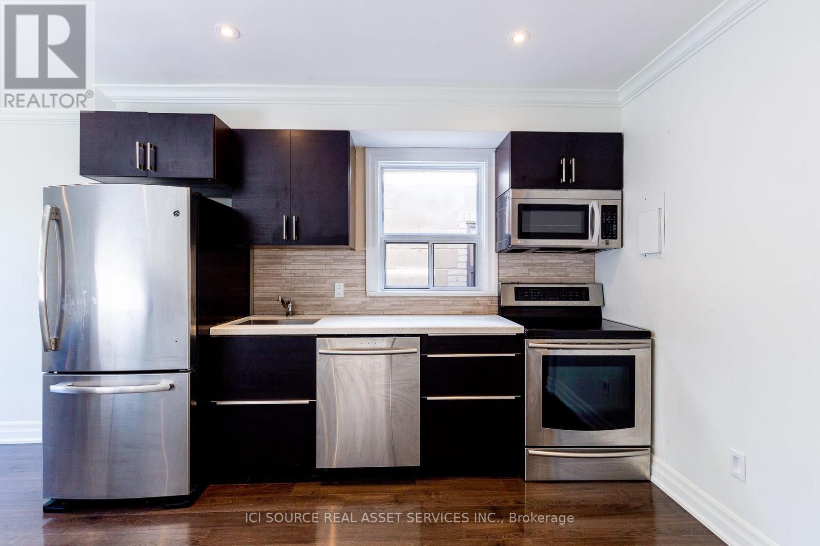 A kitchen with black cabinets and stainless steel appliances.