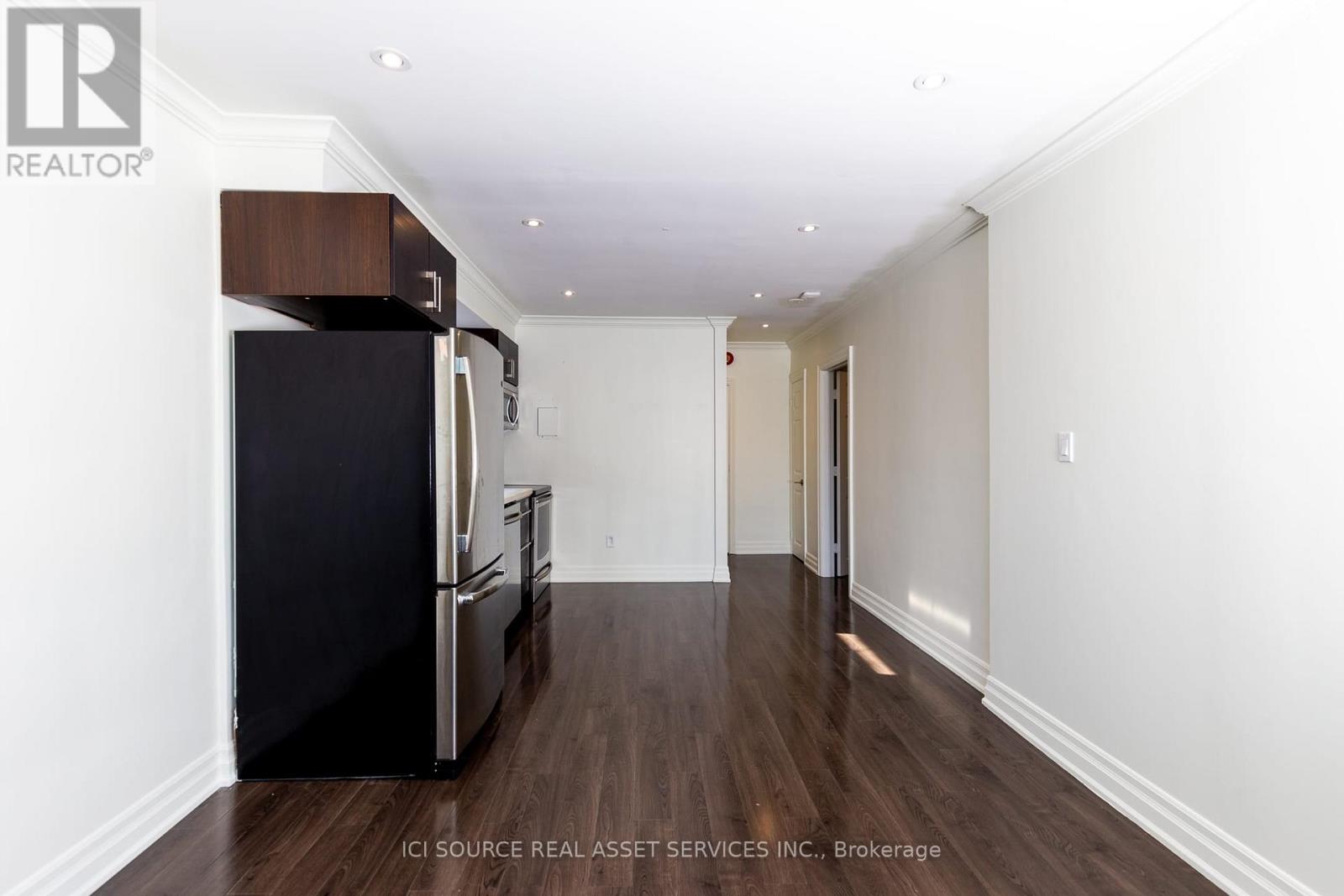 A kitchen with a black fridge and wooden floors.