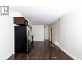 A kitchen with a black fridge and wooden floors.