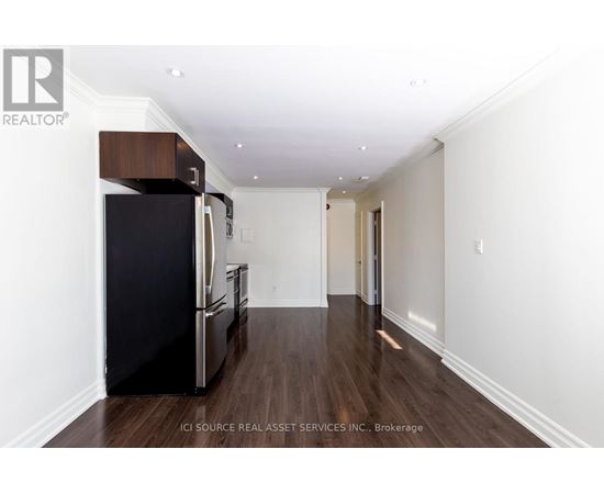 A kitchen with a black fridge and wooden floors.