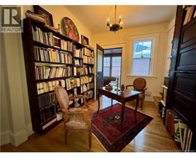 A room with a bookshelf filled with books and a chair in front of it.