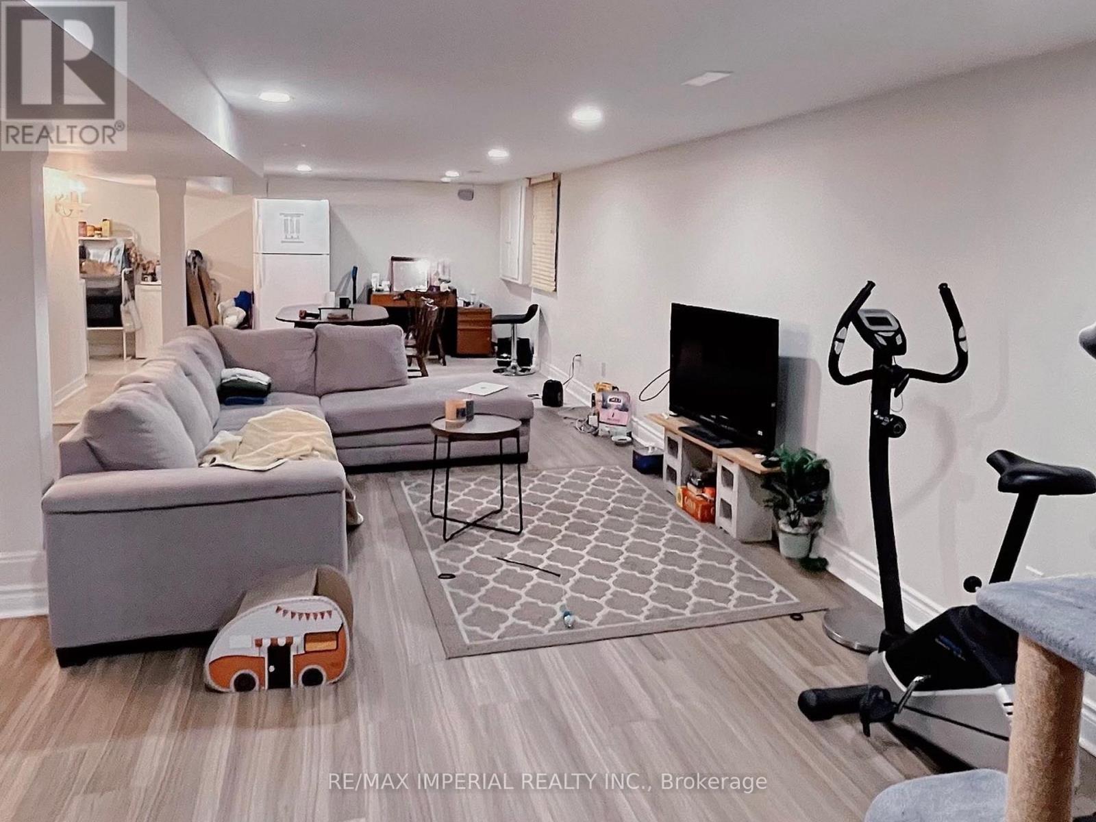 A living room with a grey couch, a black TV, and a grey rug.