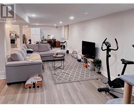 A living room with a grey couch, a black TV, and a grey rug.