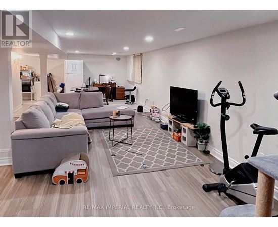 A living room with a grey couch, a black TV, and a grey rug.