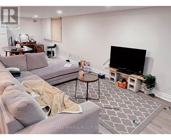 A living room with a grey couch, a black TV, and a grey and white patterned rug.
