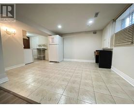 A spacious room with a tile floor and a refrigerator in the corner.