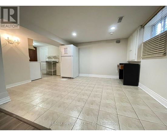 A spacious room with a tile floor and a refrigerator in the corner.