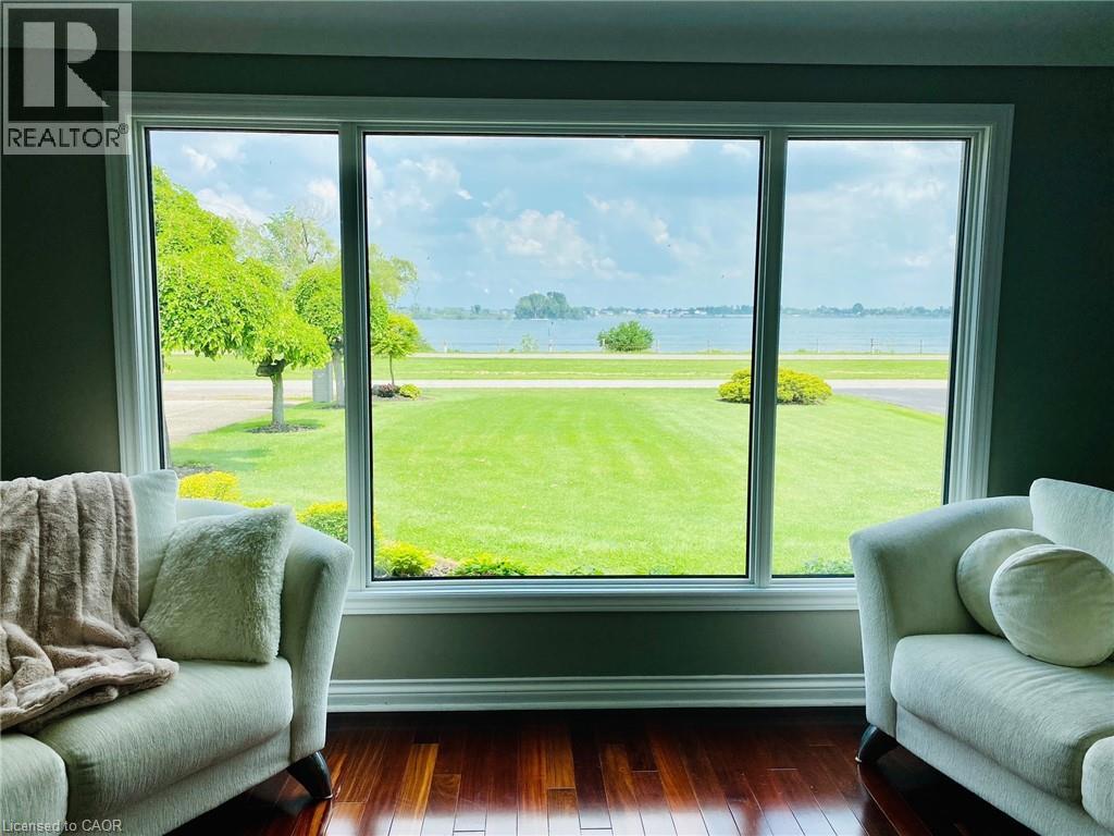 Two white couches in front of a window with a view of a green field and trees.