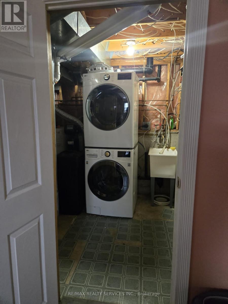 A white dryer and washer are in a small, cluttered laundry room.