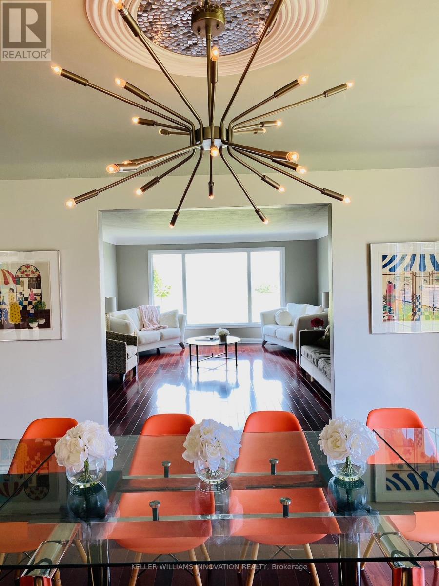 A modern dining room with a glass table and orange chairs.