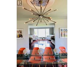 A modern dining room with a glass table and orange chairs.