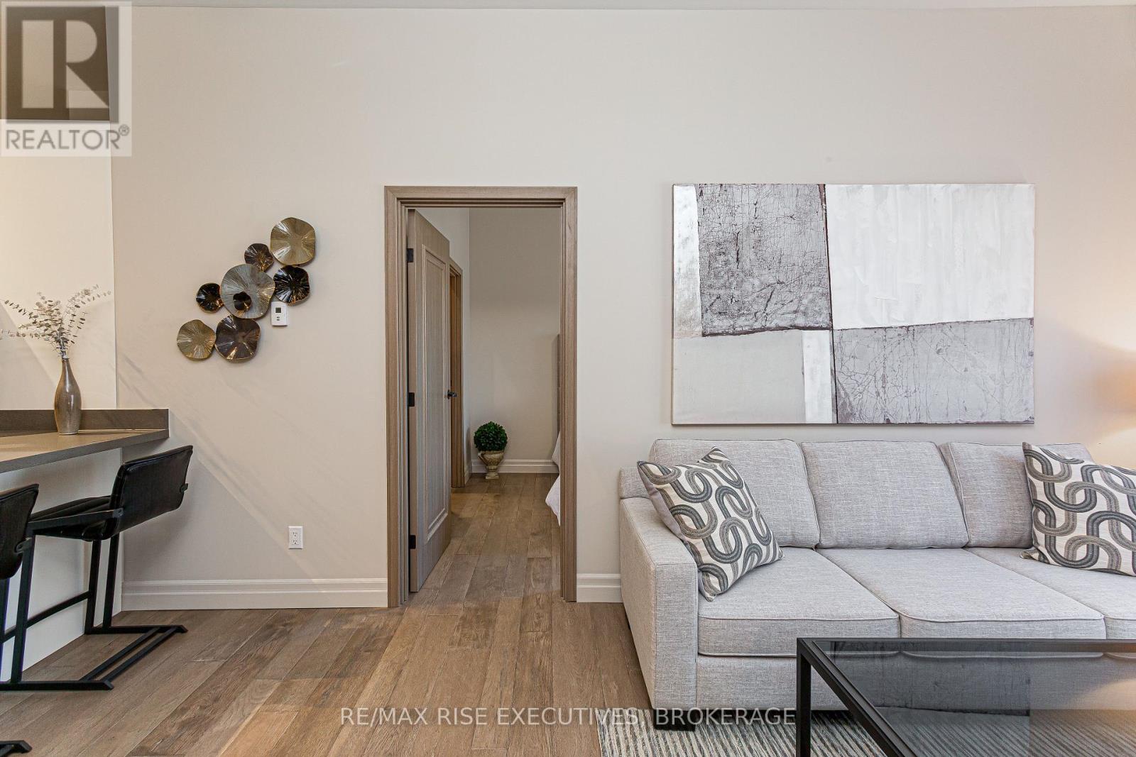 A living room with a grey couch and a painting on the wall.