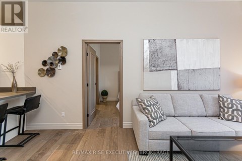 A living room with a grey couch and a painting on the wall.