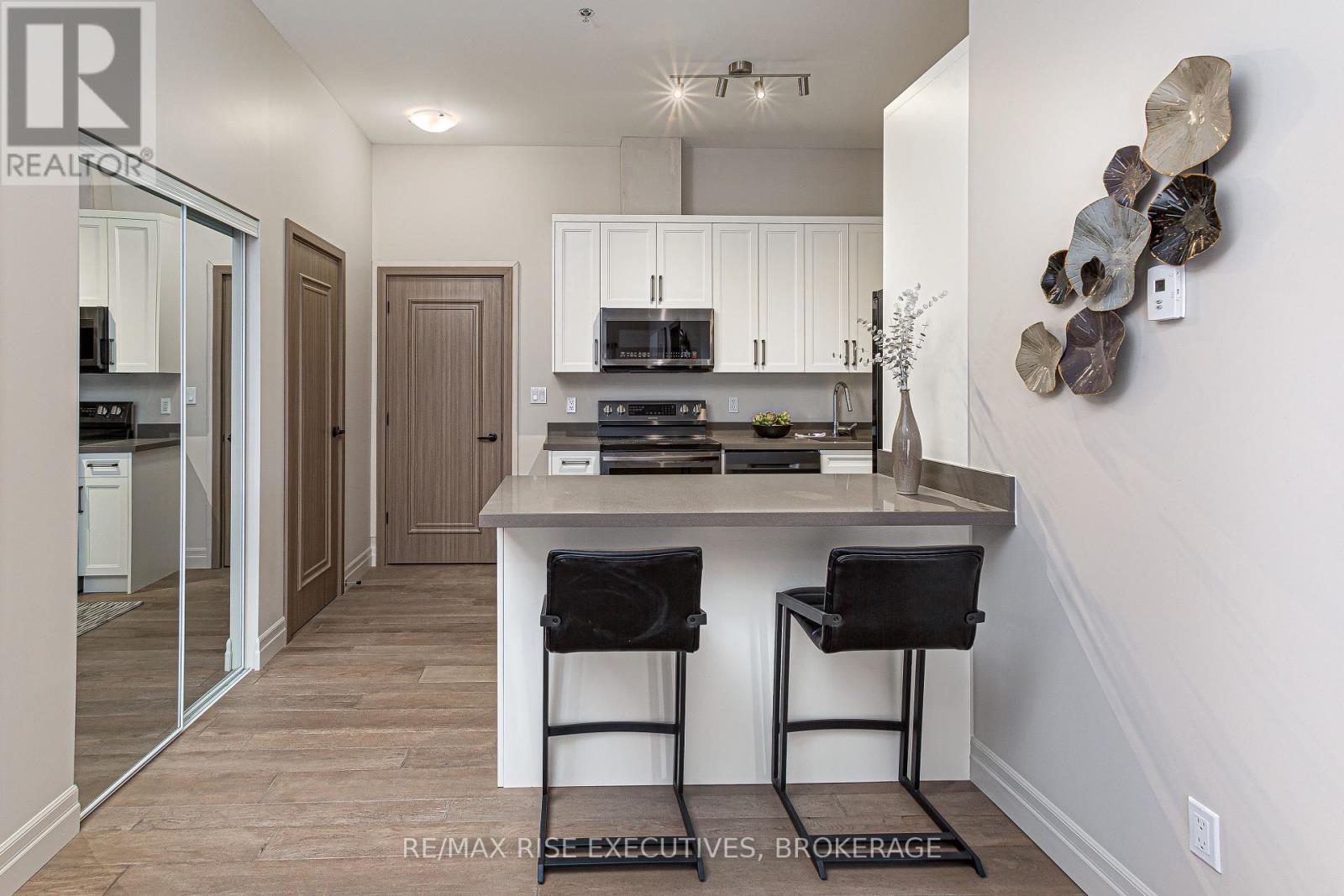 A modern kitchen with white cabinets and a wooden floor.
