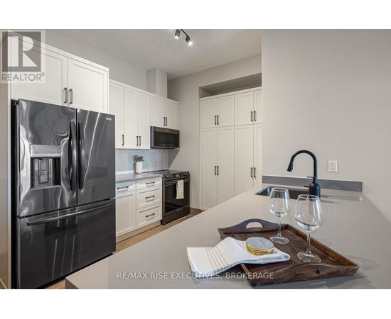 A modern kitchen with a stainless steel refrigerator and white cabinets.
