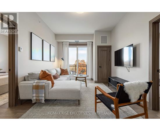 A bedroom with a bed covered in a blanket and pillows, a chair with a white furry cushion, and a flat-screen TV mounted on the wall.
