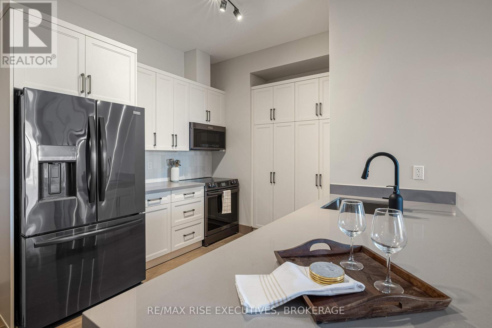 A modern kitchen with a stainless steel refrigerator and white cabinets.