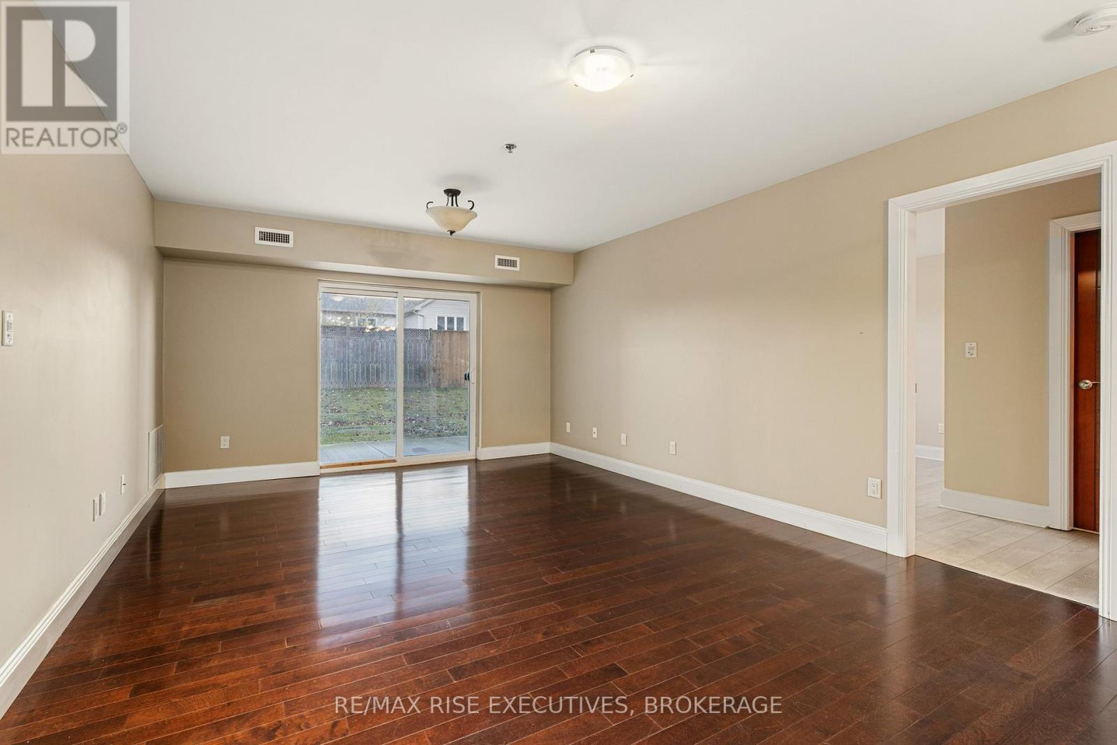 A spacious room with wooden floors and a sliding glass door leading outside.