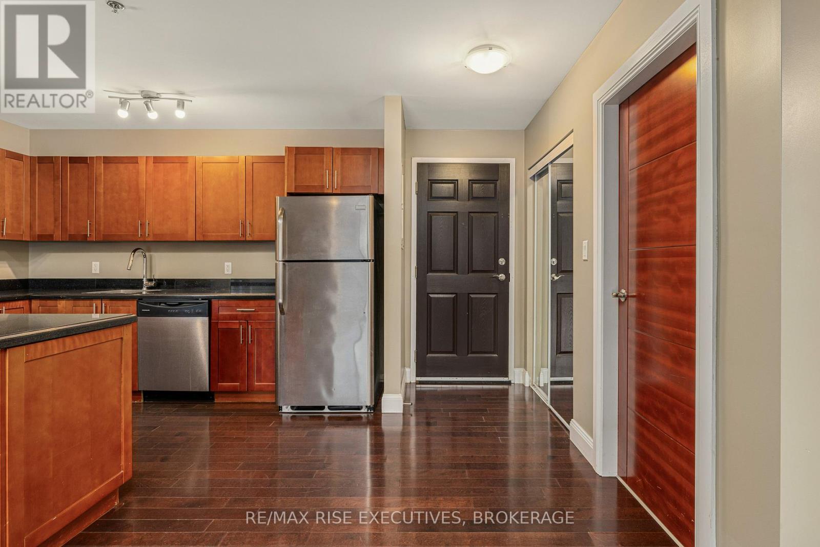 A kitchen with wooden cabinets and a stainless steel refrigerator.