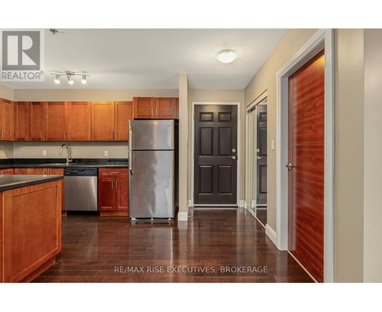 A kitchen with wooden cabinets and a stainless steel refrigerator.