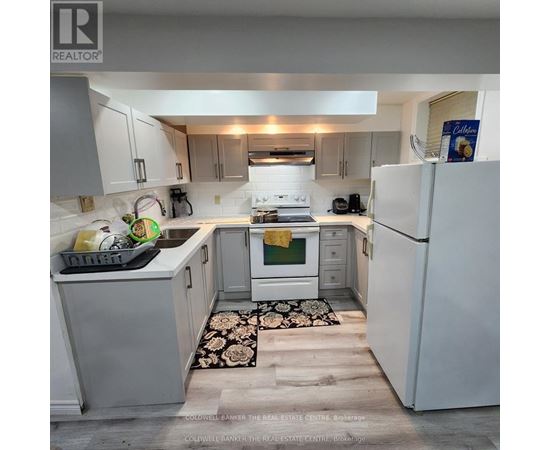 A kitchen with white appliances and a black and white rug on the floor.