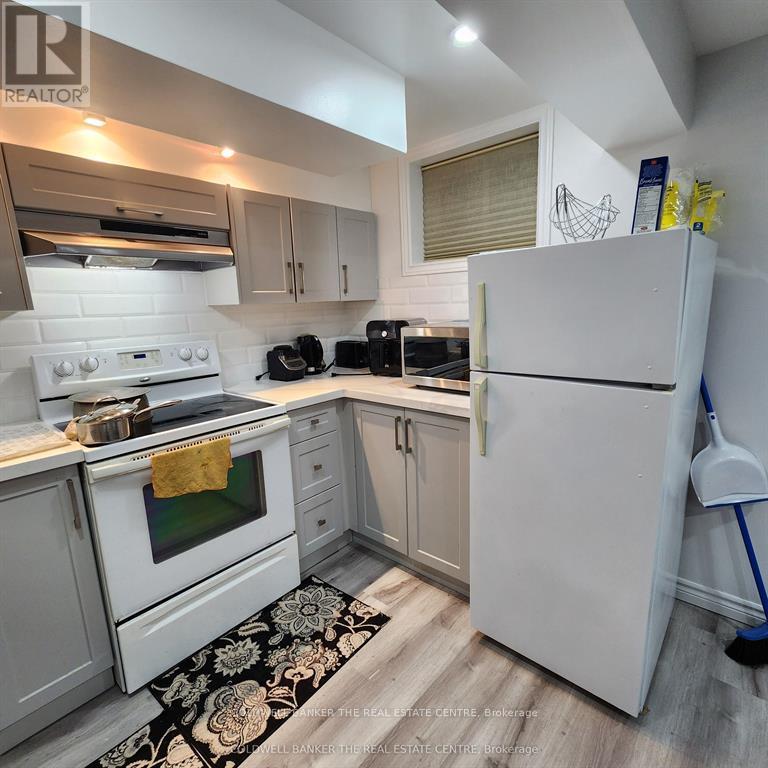 A kitchen with white appliances and a black and white rug on the floor.
