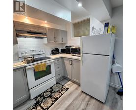 A kitchen with white appliances and a black and white rug on the floor.