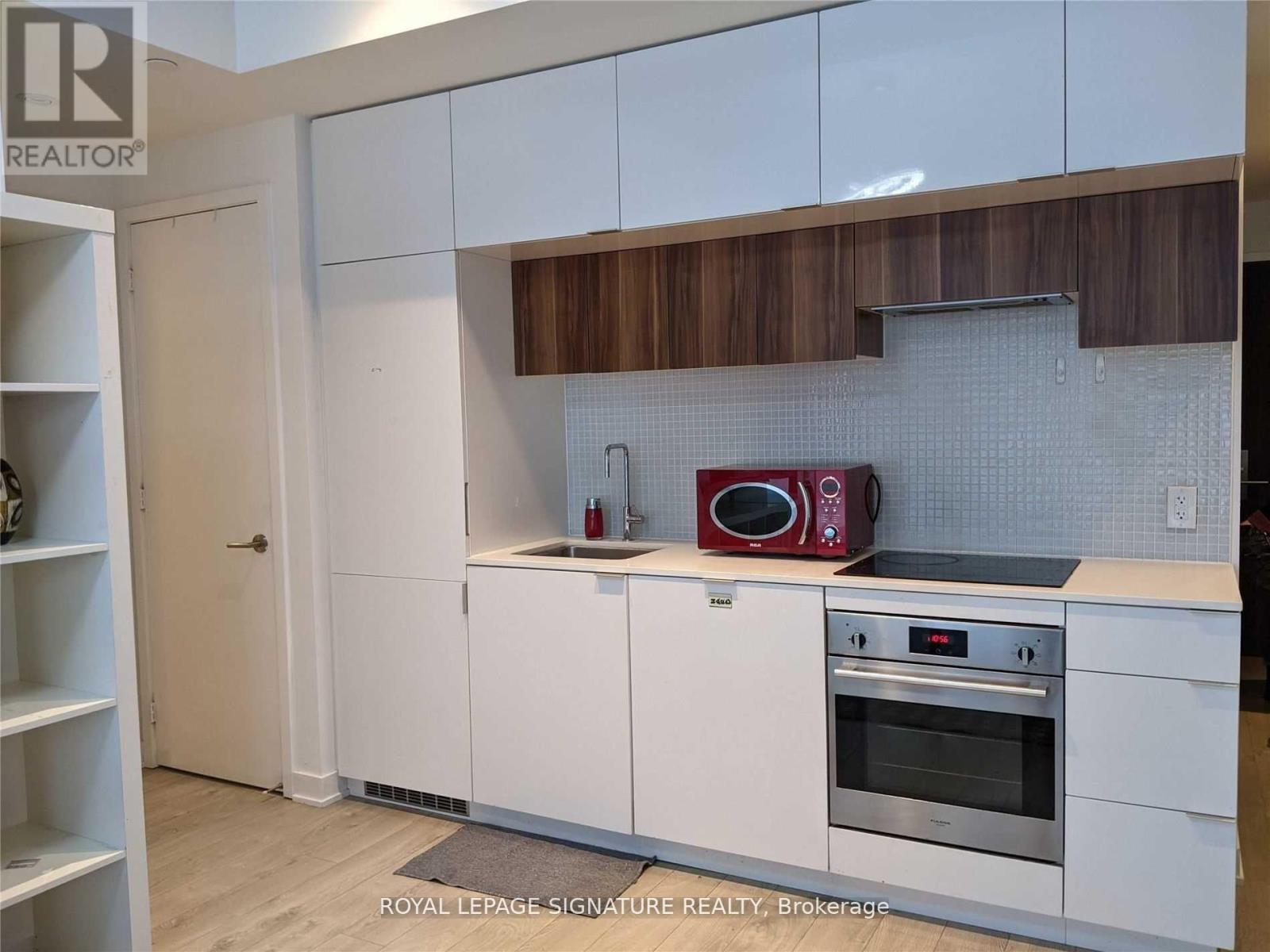 A kitchen with white cabinets and a red microwave.