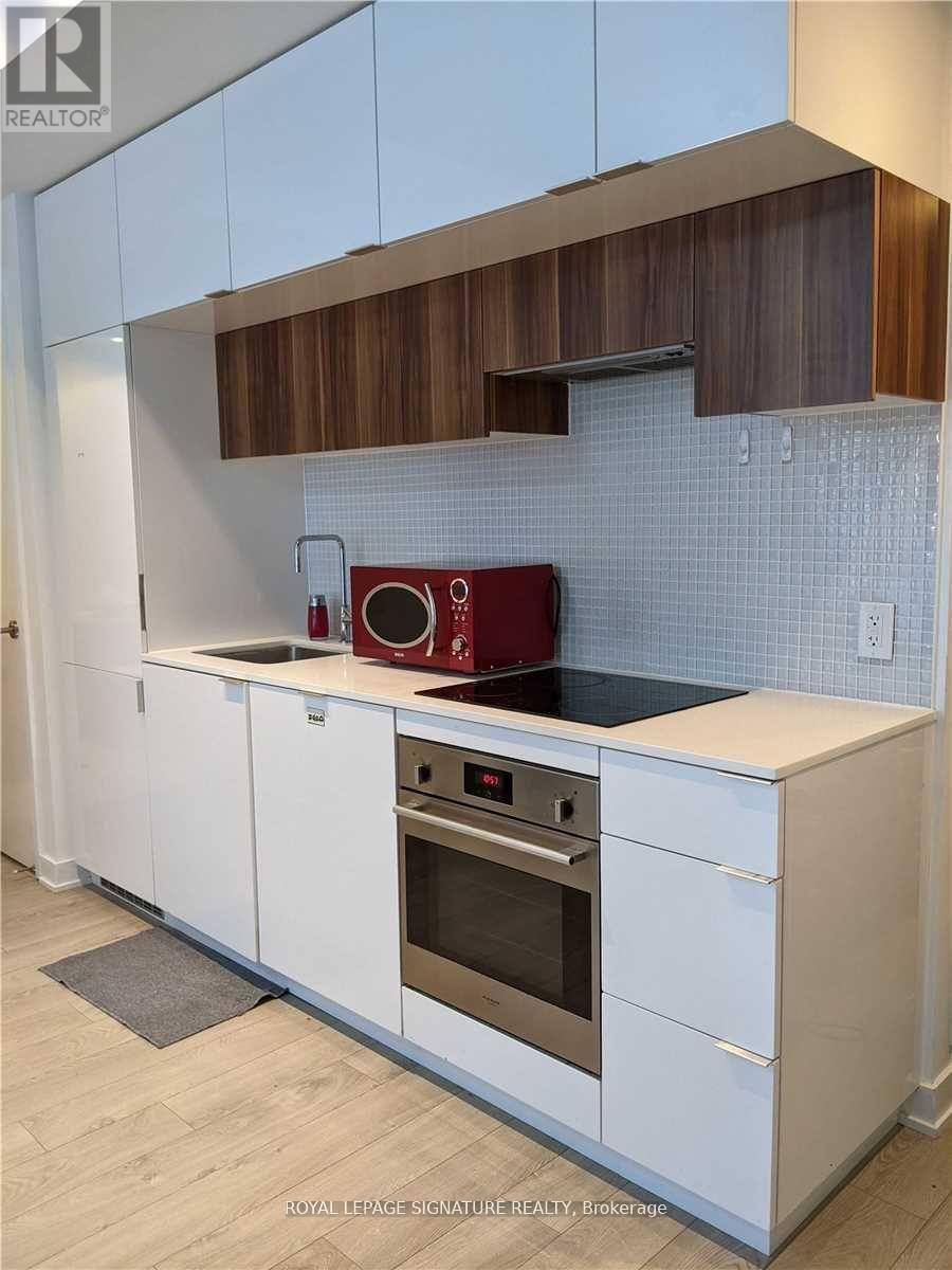 A kitchen with white cabinets and a red appliance.