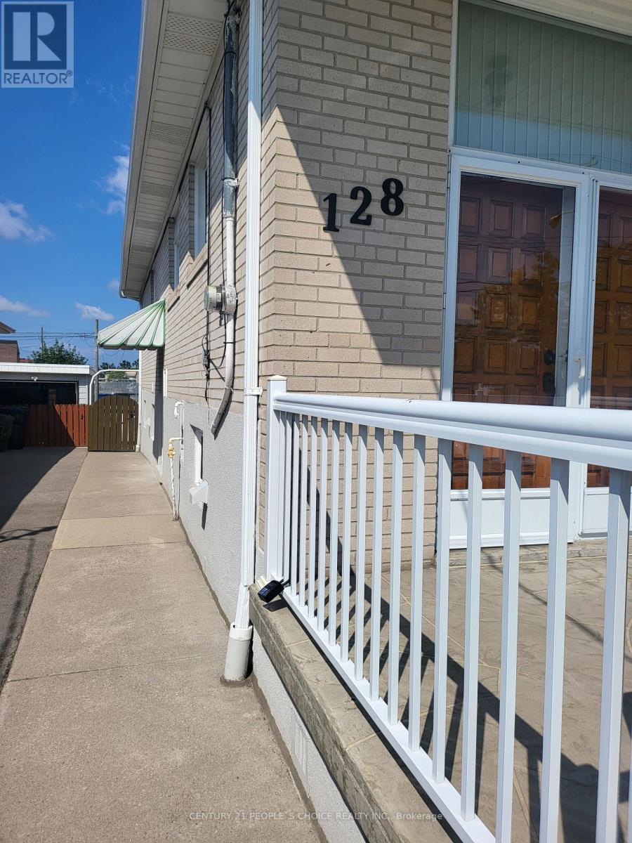 A white fence in front of a house with the number 128 on it.
