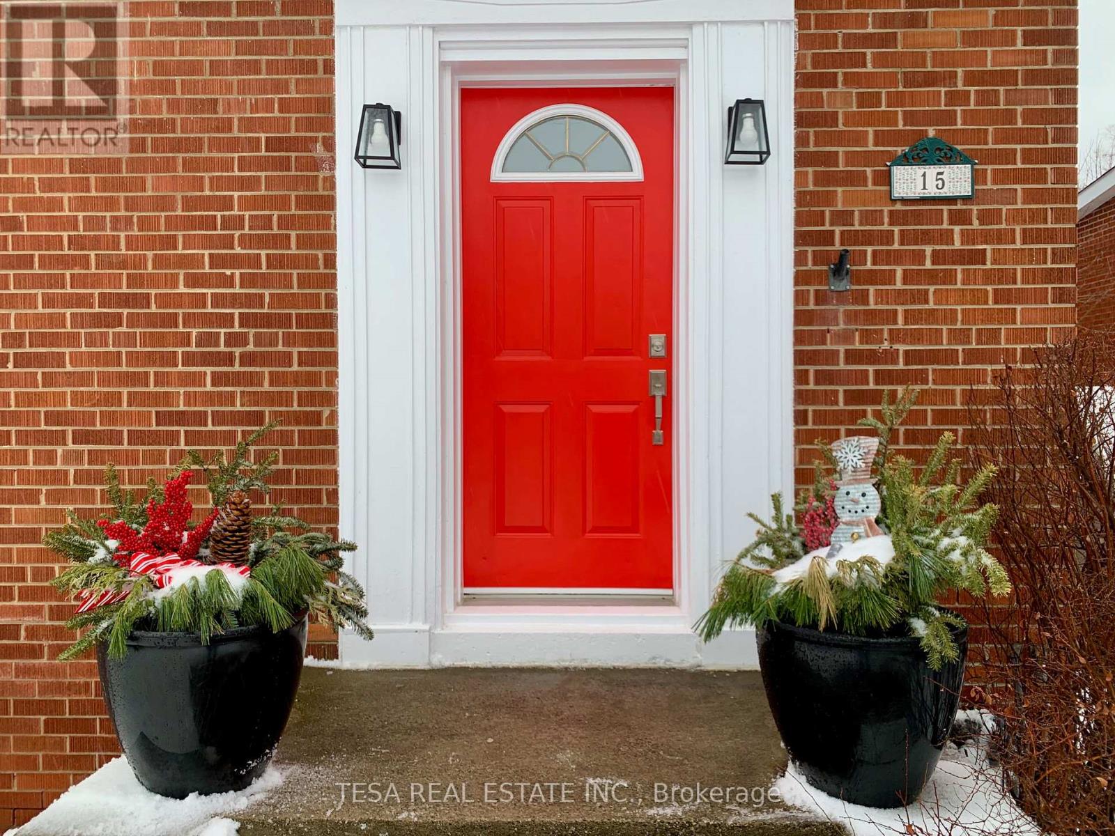 A red door with a snowman decoration in front of it.